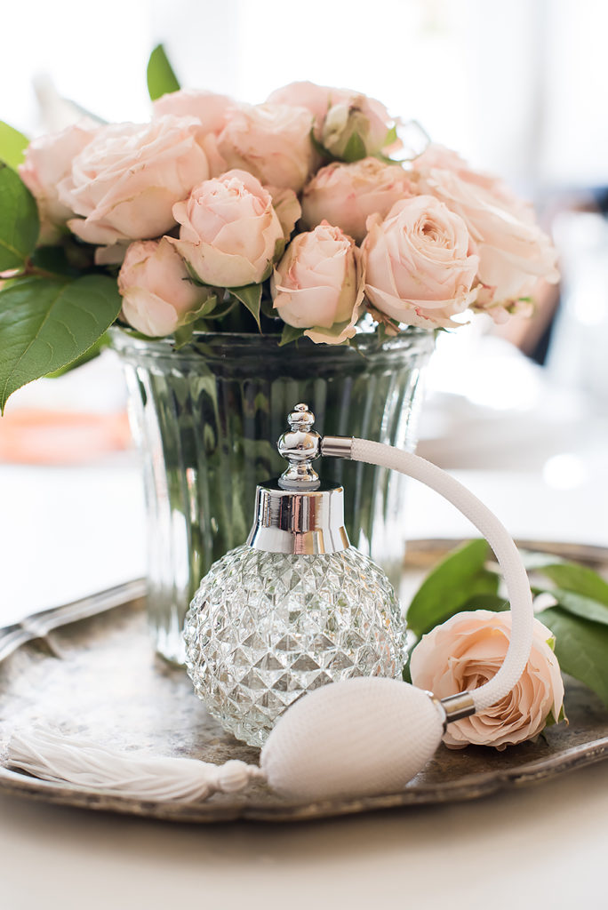Elegant composition in retro style, vintage perfume bottle and a bouquet of roses on a silver tray on ladies dressing table